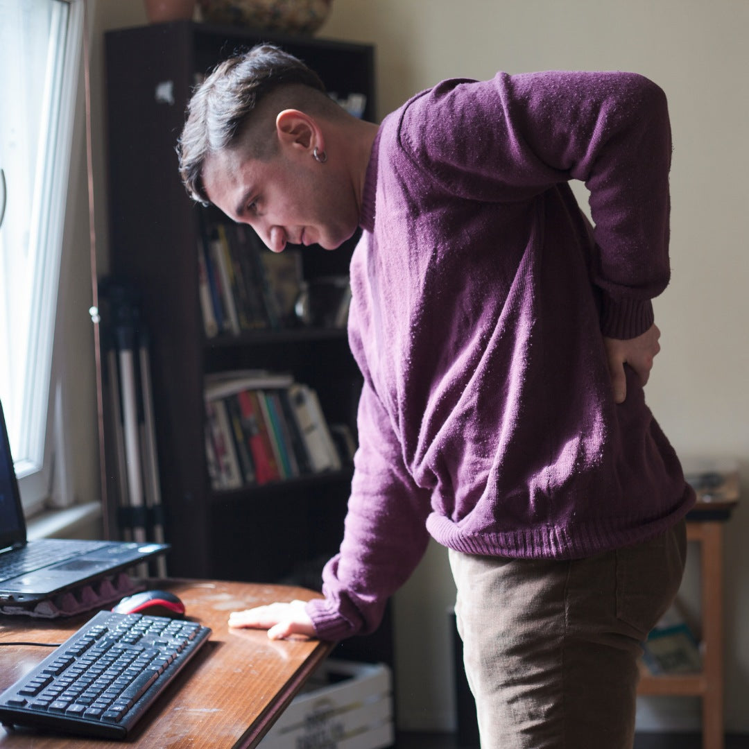 homme se tenant le bas du dos après une journée assise au bureau Image