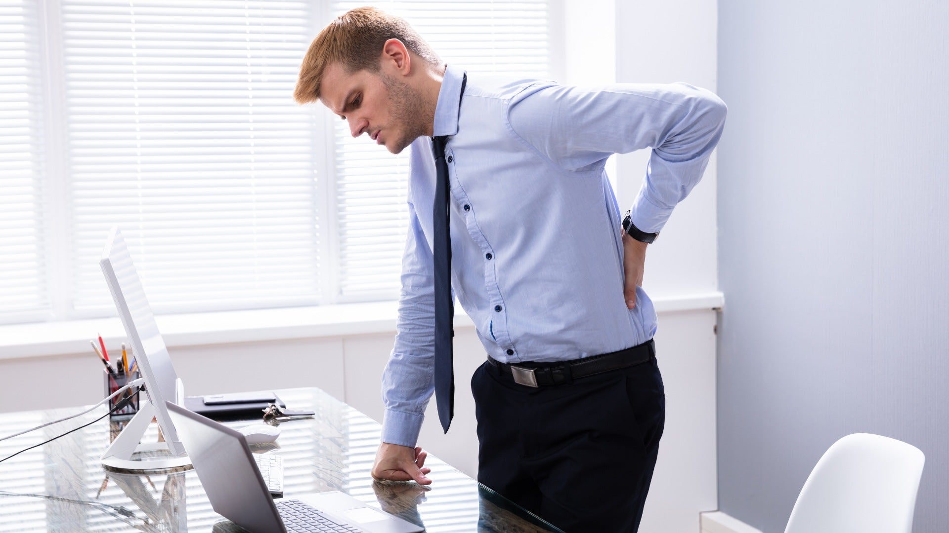homme se tenant le bas du dos, douleur lombaire après journée de travail Image