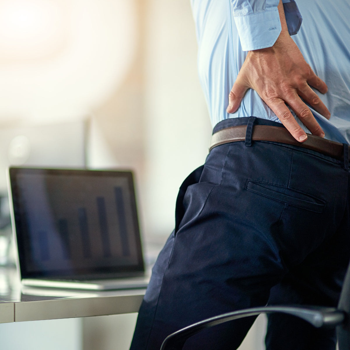 Homme au bureau ressentant une douleur dans le bas du dos après une position assise prolongée Image